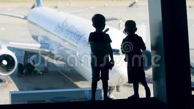 两个小男孩站在机场<strong>大</strong>窗户附近看<strong>大飞机</strong>的剪影